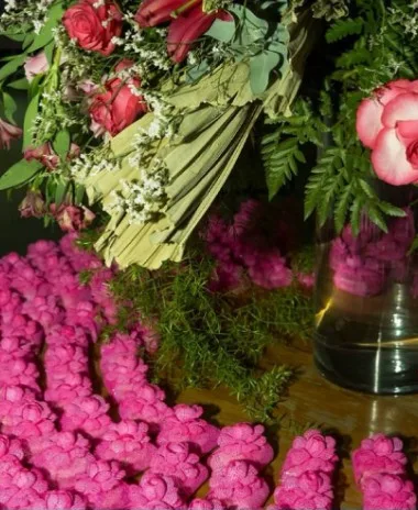 Alfajores rosa entre flores na mesa de doces de casamento